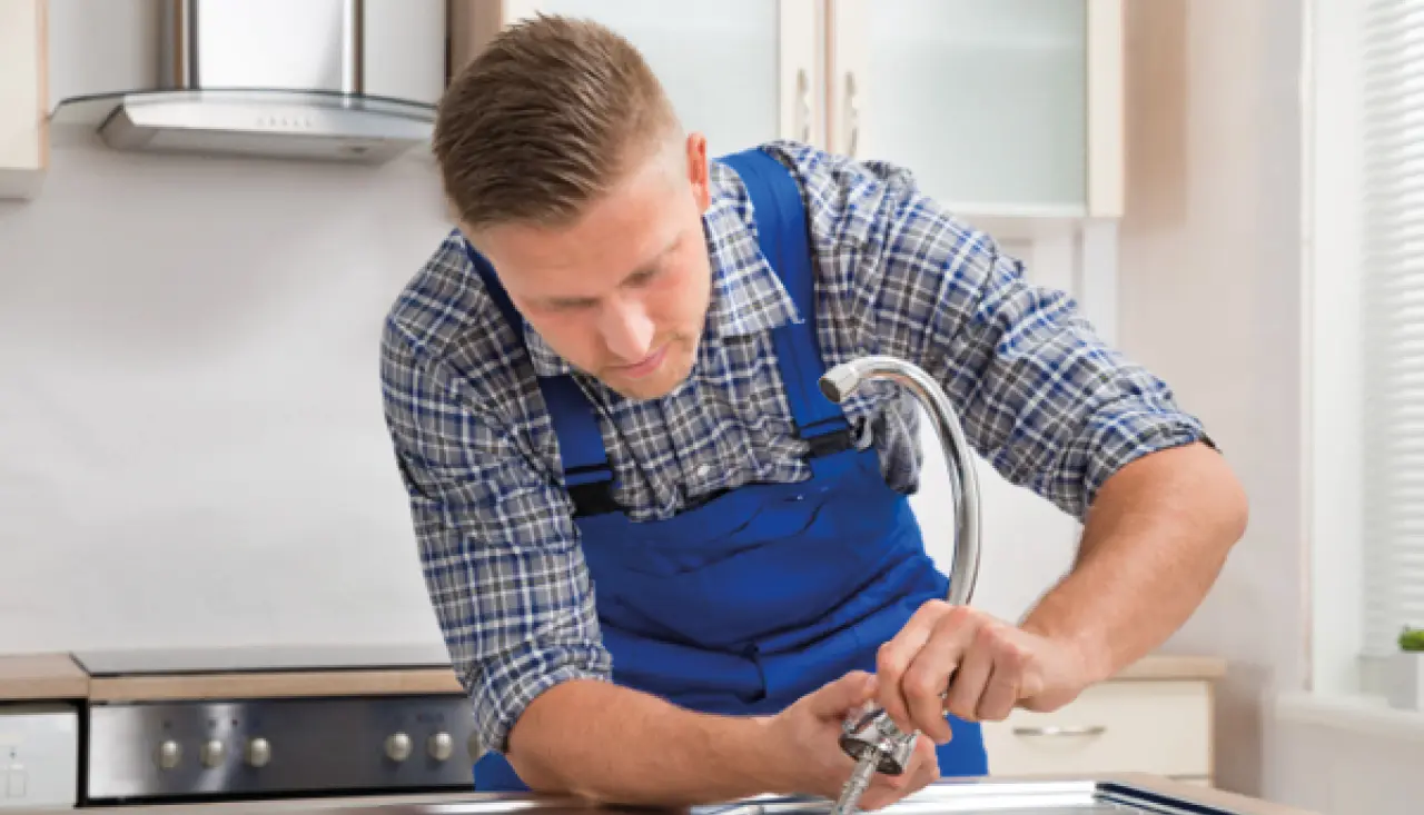 Handwerker montiert fachgerecht eine Küchenarmatur in moderner Küche. Installation, Küchenmontage und Reparaturservice für hochwertige Küchenausstattung. Fokus auf präzises Arbeiten und zuverlässigen Service.